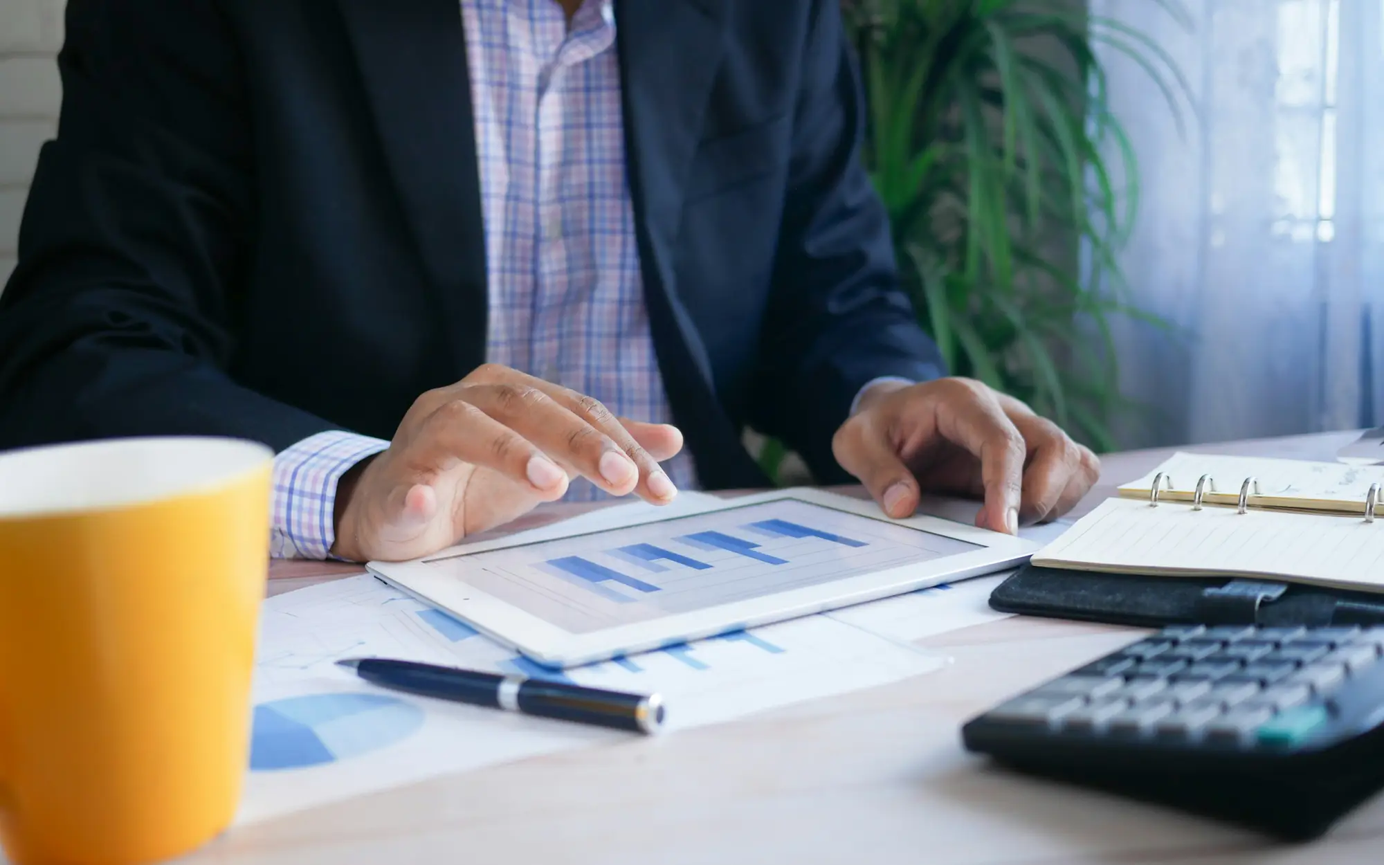 Accountant reviewing financial charts on a tablet next to a calculator