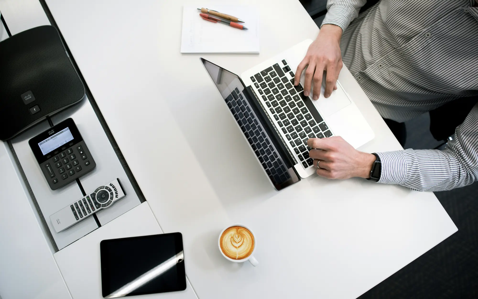 Top-down view of a person working on a laptop at a white desk