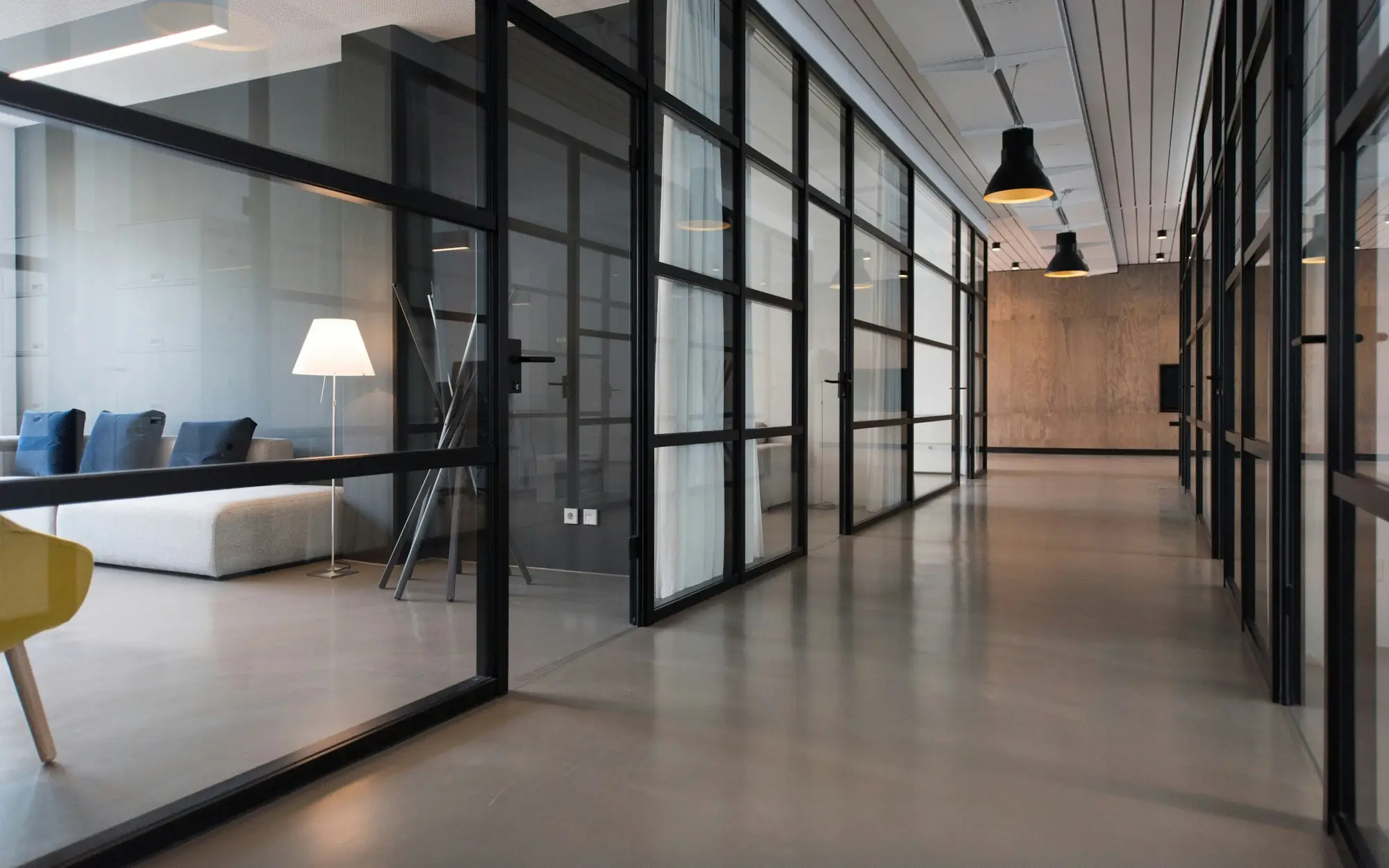 Modern office corridor with glass-walled meeting rooms
